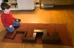 Lyonsgate Montessori School Casa student working with the Montessori Brown Stairs material that helps refine perception of size difference and relations.
