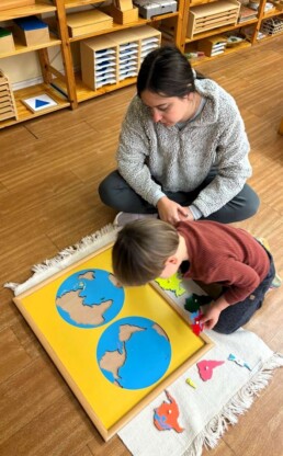 Lyonsgate Montessori School Casa student receiving a presentation with the Montessori Puzzle Map of the continents.