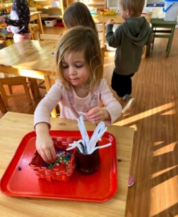 Lyonsgate Montessori School Casa student working on a holiday craft project that mirrors a Montessori fine motor skill development activity.