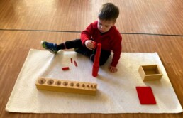 Lyonsgate Montessori School Casa student working with two different types of Montessori Cylinder materials.