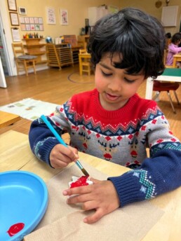 Lyonsgate Montessori School Casa student working on a Christmas craft while wearing just the right sweater.