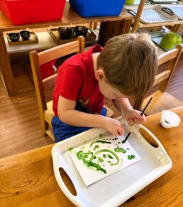 Lyonsgate Montessori School Toddler student painting with watercolour paint.
