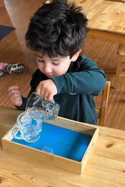 Lyonsgate Montessori School Casa student developing focus and motor skills with a Montessori Pouring activity.
