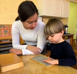 A Lyonsgate Montessori School Casa student receiving a presentation of the Montessori Rough and Smooth Board material.