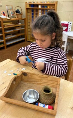 Lyonsgate Montessori School Casa student putting lots of scissor work with Montessori Snippet activities to use making a winter snowflake craft.