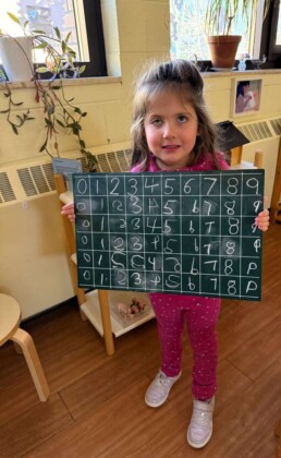 Lyonsgate Montessori School Casa student showing her work learning to write number symbols.