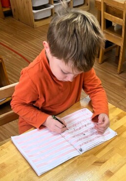 Lyonsgate Montessori School Casa student practicing writing in cursive.