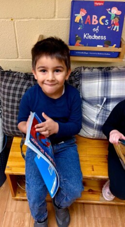 Lyonsgate Montessori School Casa student settling in to look at a book with a friend.
