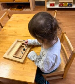 Lyonsgate Montessori School Toddler student building motor control skills by working with different types of fasteners.