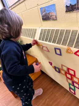 Lyonsgate Montessori School Toddler student using her creativity and problem-solving skills to strategically place her magnetic shapes and see how they fit together.
