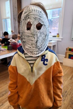 Lyonsgate Montessori School Elementary student with a theatre mask made as part of their ancient Greek studies.