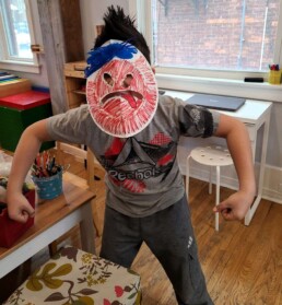 Lyonsgate Montessori School Elementary student with a theatre mask made as part of their ancient Greek studies.