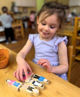 Lyonsgate Montessori School Casa student working with wooden people used to build French vocabulary.
