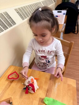 Lyonsgate Montessori School Toddler student with a plasticine creation; working with plasticine builds hand strength to support work with manipulative materials.