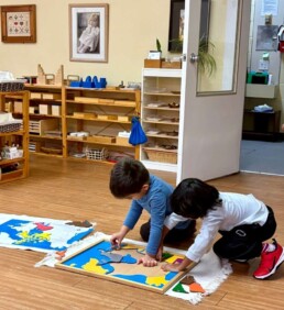 Lyonsgate Montessori School Casa students working together to complete a Montessori Puzzle Map of Canada.