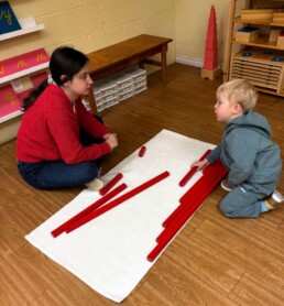 Lyonsgate Montessori School Casa student receiving a presentation of the Montessori Red Rods material that introduces children to relative length and the decimal system.