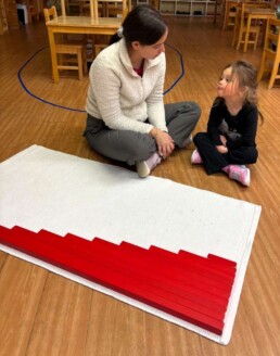 Lyonsgate Montessori School Casa student receiving a presentation of the Montessori Red Rods material that introduces children to relative length and the decimal system.