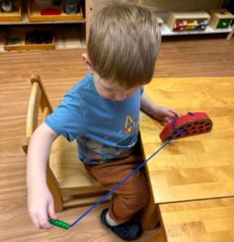 Lyonsgate Montessori School Toddler student building motor skills and concentration with a 