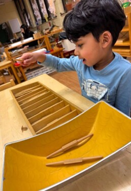 Lyonsgate Montessori School Casa student working with the Montessori Spindle Box material to associate number symbols with visual and tactile quantities, but with French numbers.