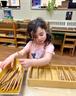 Lyonsgate Montessori School Casa student working with the Montessori Spindle Box material that associates number symbols with visual and tactile quantities.