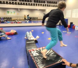 Lyonsgate Montessori School Elementary student completing an obstacle course warm-up at their winter phys. ed. martial arts experience.
