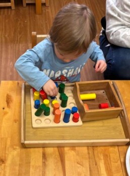 Lyonsgate Montessori School Toddler student building motor skills, and preparing for similar cylinder work in Casa.