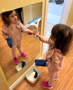 Lyonsgate Montessori School Toddler student progressing through the sequential steps of cleaning the classroom mirror.