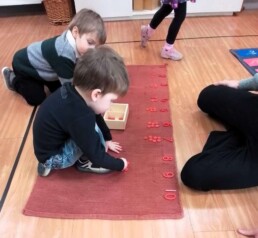Lyonsgate Montessori School Casa students working together with the Montessori Numerals and Counters material to build a sense of quantity relative to number symbols.