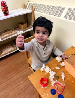 Lyonsgate Montessori School Toddler student building hand strength and imagination with play dough.