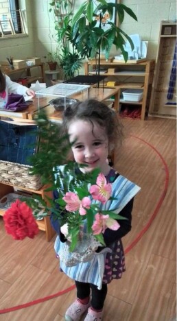 Lyonsgate Montessori School Casa student showing off her Montessori Flower Arranging activity work.
