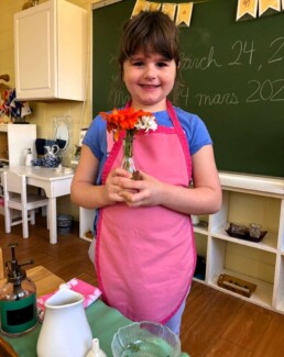 Lyonsgate Montessori School Casa student proudly displaying the results of her flower arranging work.