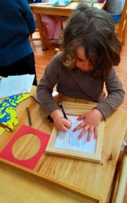 Lyonsgate Montessori School Casa student working with the iconic Montessori Metal Insets material that develops dexterity and control, introduces geometry vocabulary, and is an artistic activity.