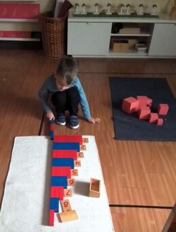 Lyonsgate Montessori School Casa student building familiarity with the decimal number system with the Montessori Number Rods material.