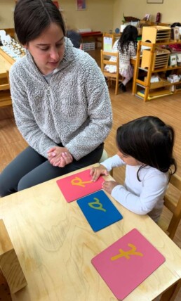 Lyonsgate Montessori School Casa student beginning the journey into writing with the Montessori Sandpaper Letters material.