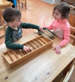 Lyonsgate Montessori School Casa students working together with the Montessori Spindle Box material.