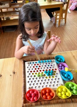 Lyonsgate Montessori School Casa student developing focus and fine motor skills by using tongs to recreate a pattern.
