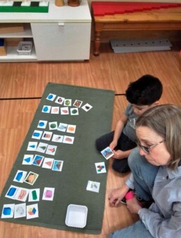 Lyonsgate Montessori School Casa student matching objects to geometric shapes, and building French vocabulary with his French language classroom assistant.