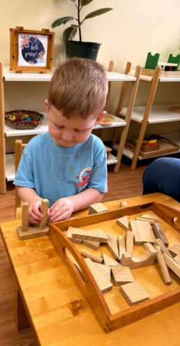 Lyonsgate Montessori School Toddler student experiencing concentration, creativity, and motor control with wooden blocks.