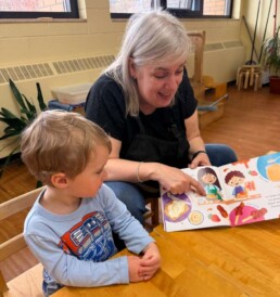 Lyonsgate Montessori School Toddler student enjoying a book with his Montessori guide.