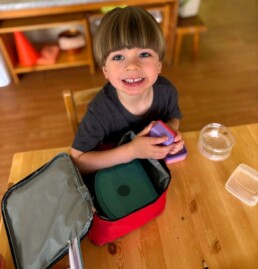 Lyonsgate Montessori School Casa student opening and closing different types of containers to develop practical life skills and to practice problem solving while building hand strength and motor skills.