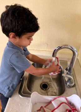 Lyonsgate Montessori School Toddler student helping his class by preparing the damp cloth napkins for lunch.