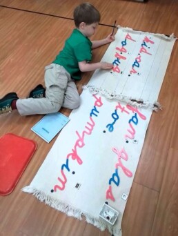 Lyonsgate Montessori School Casa student working with the Montessori Moveable Alphabet material to begin learning how to build words.