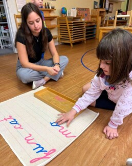 Lyonsgate Montessori School Casa student receiving a presentation of the Montessori Moveable Alphabet material to build early writing and spelling skills.