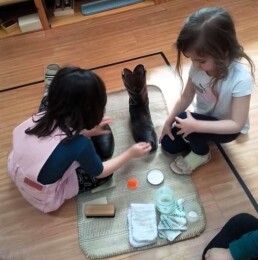 Lyonsgate Montessori School Casa students engaged in the Montessori Polishing Leather activity; the polishing jobs are increasingly complex in terms of steps but produces an observable result.