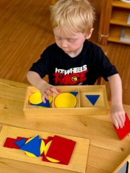 Lyonsgate Montessori School Casa student getting ready to work with the Montessori Graded Figures material which he will use to superimpose shapes upon each other.