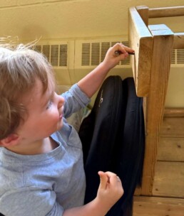 Lyonsgate Montessori School Toddler student taking the tools and fasteners material out into the wider world to make sure the classroom is safe and sturdy.