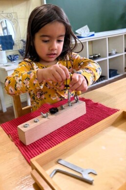 Lyonsgate Montessori School Casa student learning to use different tools and fasteners to build fine motor skills, hand strength, and lifelong practical skills.