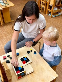 Lyonsgate Montessori School Casa student receiving a presentation of the Montessori Trinomial Cube material, which is a puzzle at this stage while serving as a conceptual introduction to abstract and algebraic thinking.