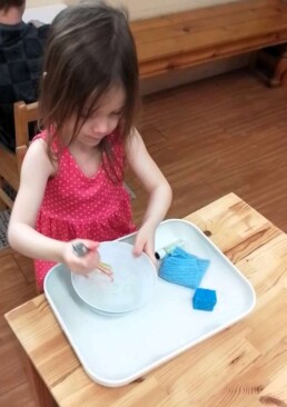 Lyonsgate Montessori School Casa student whisking up some bubbles, which is a fun activity that builds hand strength and dexterity.