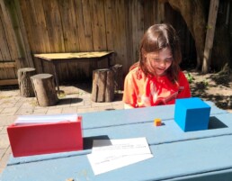 Lyonsgate Montessori School Elementary student working with the Montessori Verb Command Cards material in the outdoor classroom.